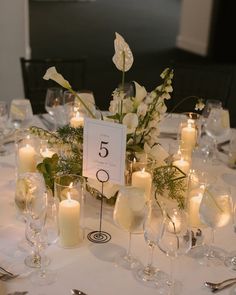 the table is set with candles, flowers and wine glasses for an elegant wedding reception