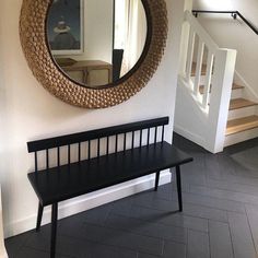 a wooden bench sitting under a round mirror next to a stair case in a house