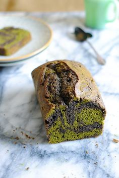 a loaf of cake sitting on top of a marble counter next to a cup and saucer