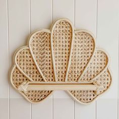 a bamboo scallop hanging on the wall in front of a white tiled wall