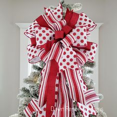 a large red and white bow on top of a christmas tree