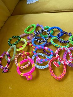 a bunch of colorful bracelets sitting on top of a yellow couch next to each other