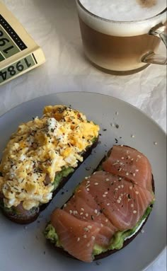 a plate with two pieces of bread and an egg salad on it next to a cup of coffee