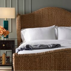 a wicker bed with white sheets and pillows