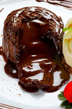 a chocolate dessert with ice cream and strawberries on the side is ready to be eaten