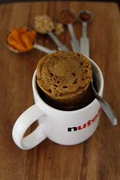 a cup filled with cookies and spoons on top of a wooden table