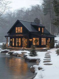 a house is lit up with christmas lights by the water