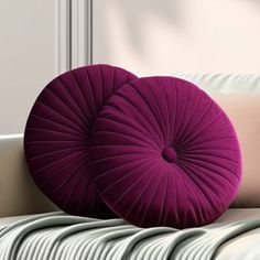 two purple pillows sitting on top of a white couch