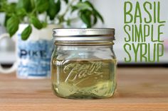 a jar filled with liquid sitting on top of a wooden table next to a potted plant