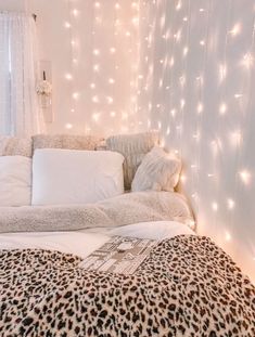 a leopard print comforter on a bed with white sheets and lights in the background