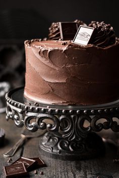 a chocolate cake sitting on top of a metal plate next to some pieces of chocolate