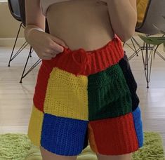 a woman wearing colorful knitted shorts while holding her cell phone