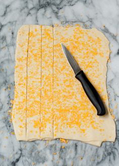 a knife is on top of some crackers that have been cut into squares and are sitting on a marble surface