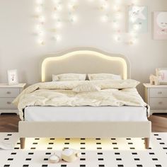 a white bed sitting in a bedroom next to a night stand with lights on it