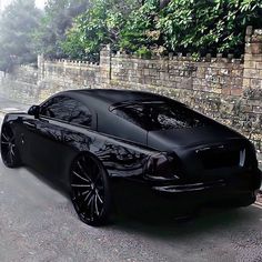 a black sports car parked in front of a brick wall