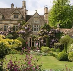 a large house surrounded by lush green trees and flowers