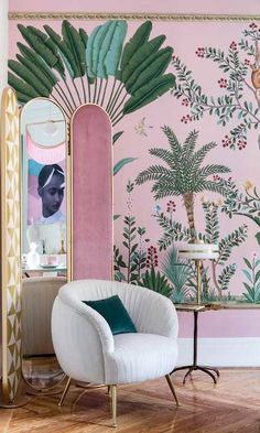 a chair and mirror in front of a pink wall with palm tree mural on it