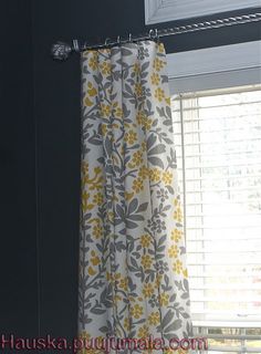 the curtains are hanging in front of the window with yellow and gray flowers on them