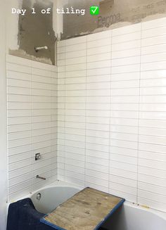 a bathtub being installed in a bathroom with white tiles on the walls and floor