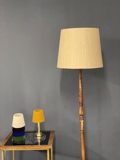 a lamp sitting on top of a table next to a wooden stick with a yellow shade