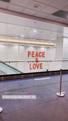 there is a sign that says peace and love on the wall behind an escalator