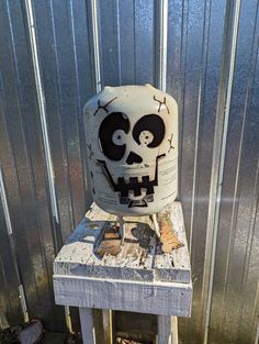 a white and black skull sitting on top of a wooden table next to a metal wall