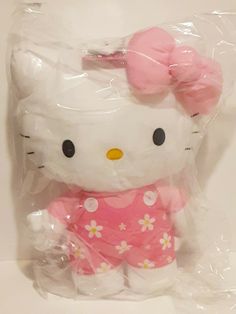 a hello kitty stuffed animal in a plastic bag on a white surface with pink bows