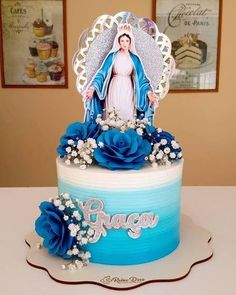 a blue and white cake decorated with an image of the virgin mary on it's top