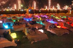 a large group of people laying on top of beds covered in blankets and glowing lights