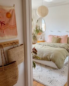 a bed room with a neatly made bed next to a mirror and hanging baskets on the wall