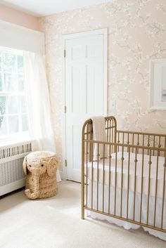 a baby's crib in the corner of a room with pink and white wallpaper