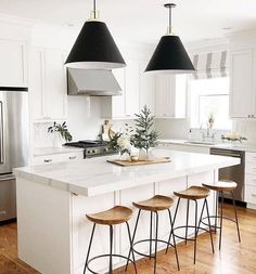 a kitchen with white cabinets and black pendant lights