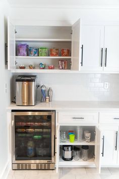 a kitchen with white cabinets and stainless steel appliances, including an open refrigerator freezer