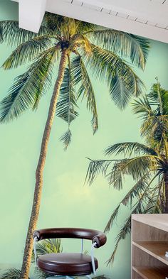 a palm tree painted on the side of a wall next to a brown leather chair