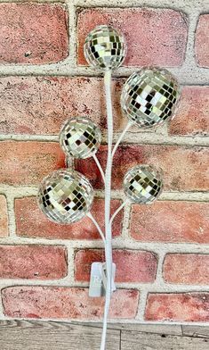 three disco ball lights on a brick wall in front of a red brick wall with a white cord