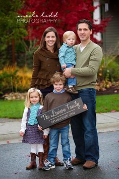 a family posing for a photo in front of their home with the sign that says, the