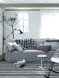 a living room with black and white striped rugs on the floor next to a gray couch