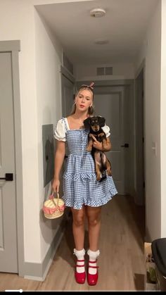 a woman in a blue dress holding a small dog