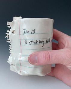 a hand holding a coffee cup with writing on it