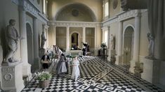 a large room with statues and sculptures on the walls, in front of a black and white checkered floor