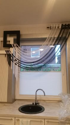 a kitchen sink under a window with sheer curtains