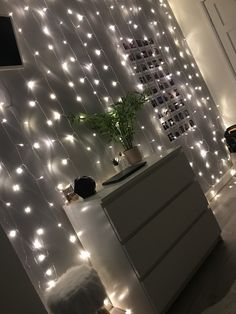 a white dresser sitting next to a wall covered in lights