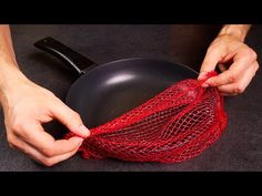 a person holding a red net over a frying pan