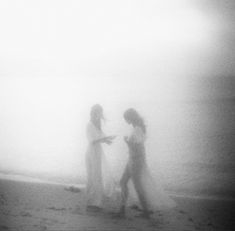 two women walking on the beach in the fog