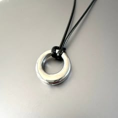 Silver Circle Pendant on Black Satin Cord Necklace Unisex  20 inch length  Pendant width 0.9 inches  CARE:  Stainless Steel:   Use a polishing cloth to gently wipe this item clean, then remove any remaining tarnish with mildly diluted soap. Rinse with warm water and dry thoroughly.   STORAGE:  When not in use, store your item in the provided complimentary jewelry pouch. Cord Necklace With Pendant, Waxed Cord Jewelry With Round Pendant For Gift, Circle-shaped Amulet Jewelry As A Gift, Black Circular Metal Necklace, Black Cord Necklace Pendants, Black Waxed Cord Pendant Jewelry, Soft Clothing, Y2k Jewelry, Hair Bangs