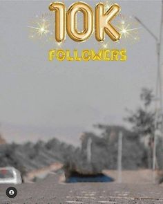 the words 10k followers are spelled with gold balloons in front of a street scene