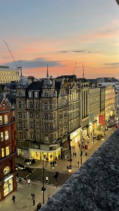 a city street at dusk with people walking on the sidewalk and buildings in the background