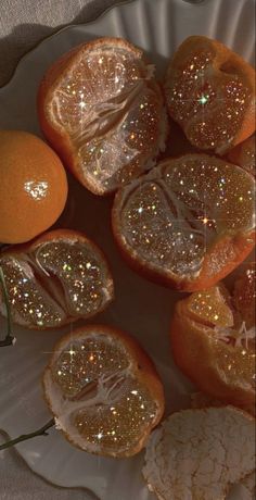 some oranges that have been cut in half on a white plate with silver glitter