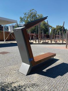 a wooden bench sitting in the middle of a park next to a metal structure and trees