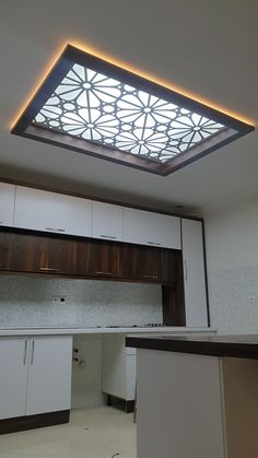 an empty kitchen with white cabinets and a skylight above the stove top, is seen in this image